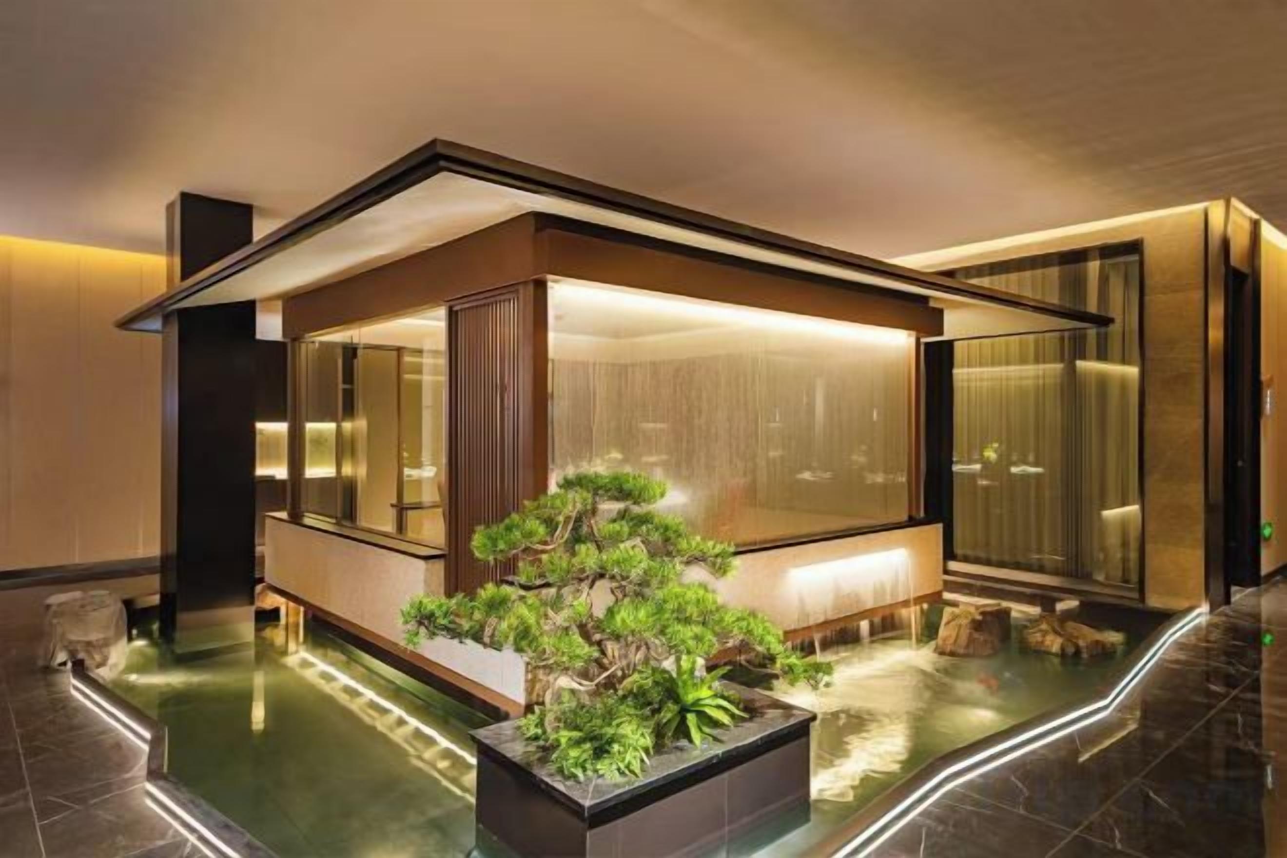 A modern interior with a glass enclosure, a water feature, and a well-maintained plant.