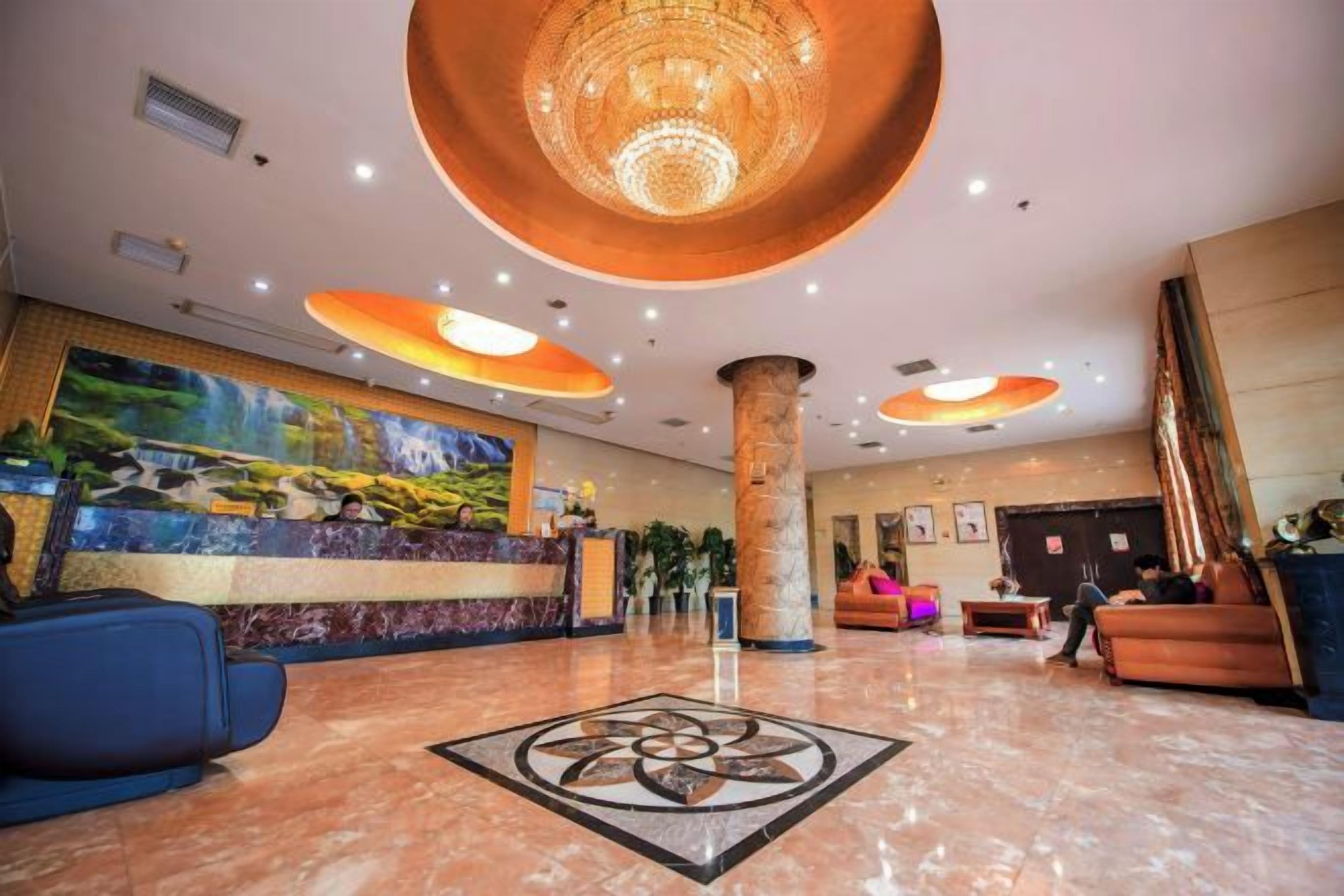 Un hall d’hôtel comprenant un comptoir d’accueil, un espace salon et un grand lustre.