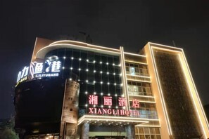 Hotel com letreiros iluminados, fachada moderna e entrada destacada.