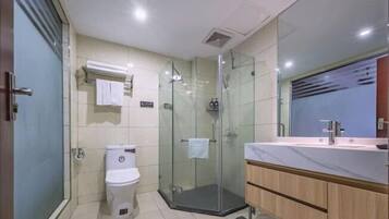 A modern bathroom with a glass shower enclosure, a toilet, and a vanity with a mirror.