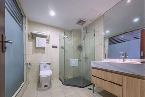 A modern bathroom with a glass shower enclosure, a toilet, and a vanity with a mirror. - Xiangli Hotel (Shawan Park Subway Station, Changsha High Speed Railway South Station) (Changsha)