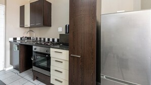 Una cocina moderna con armarios de madera oscura, un refrigerador de acero inoxidable y un horno empotrado.
