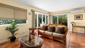 A living room with a sofa, glass coffee table, and a potted plant.
