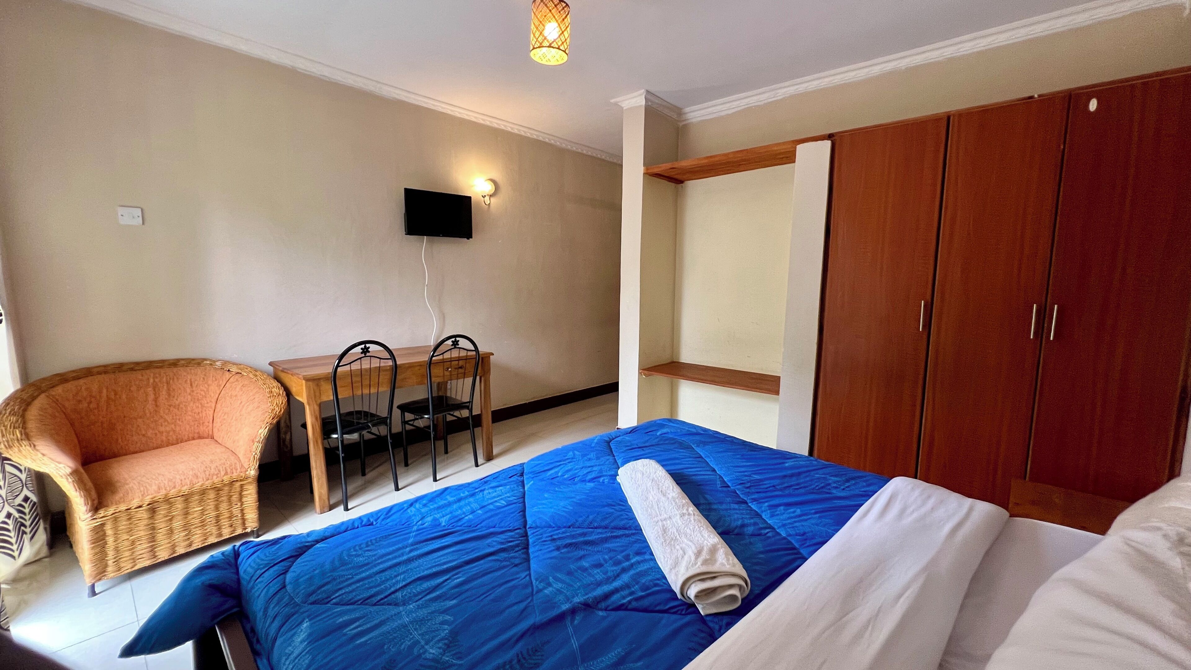Un dormitorio con cama, una silla, una mesa, un televisor y un armario.