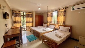 A hotel room with two single beds, a wooden desk, a chair, a TV, and a window with curtains. - Runako Lodge (Arusha)
