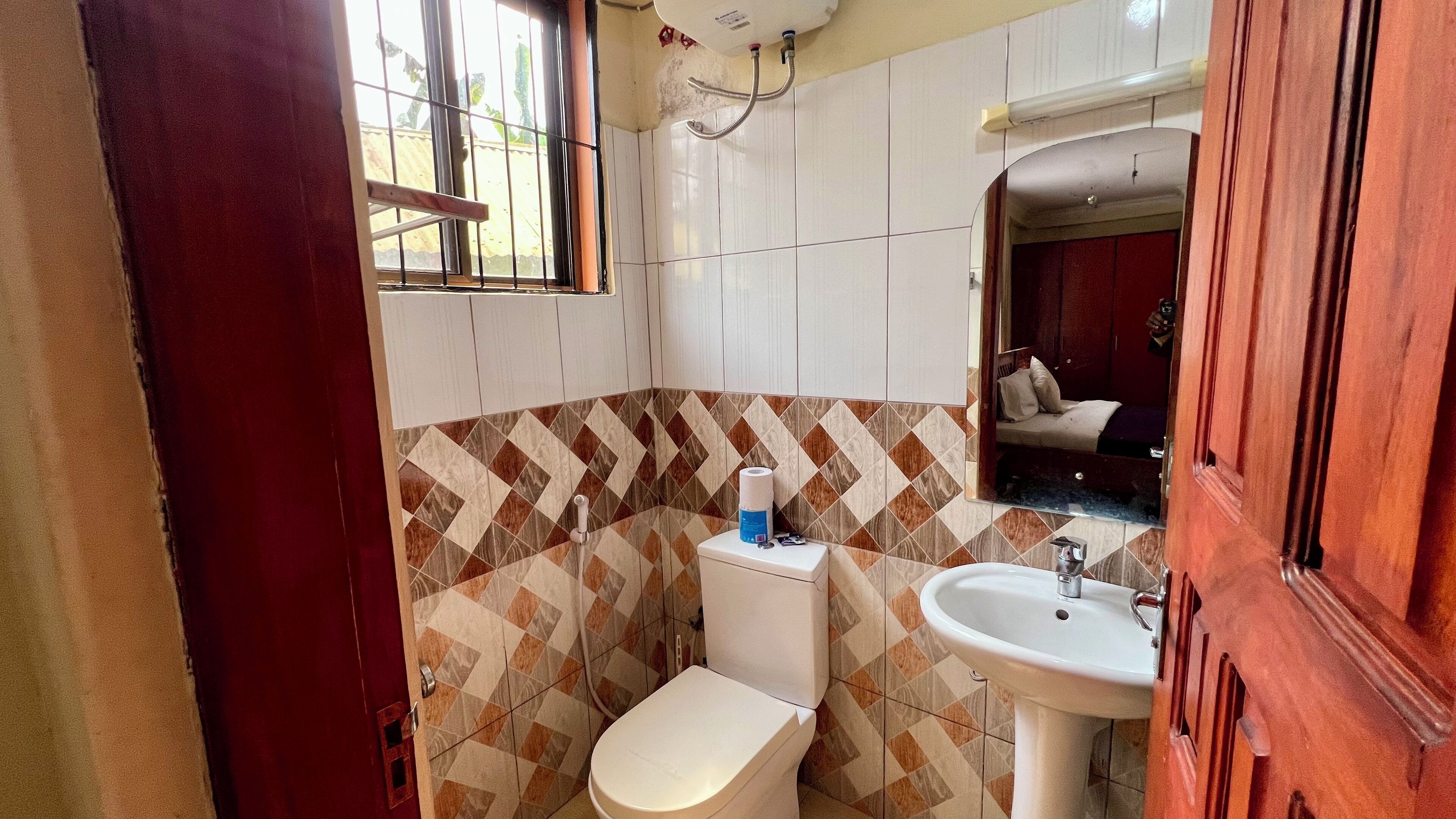 Egy kis fürdőszoba, amelyben WC, mosdókagyló és egy ablak található.