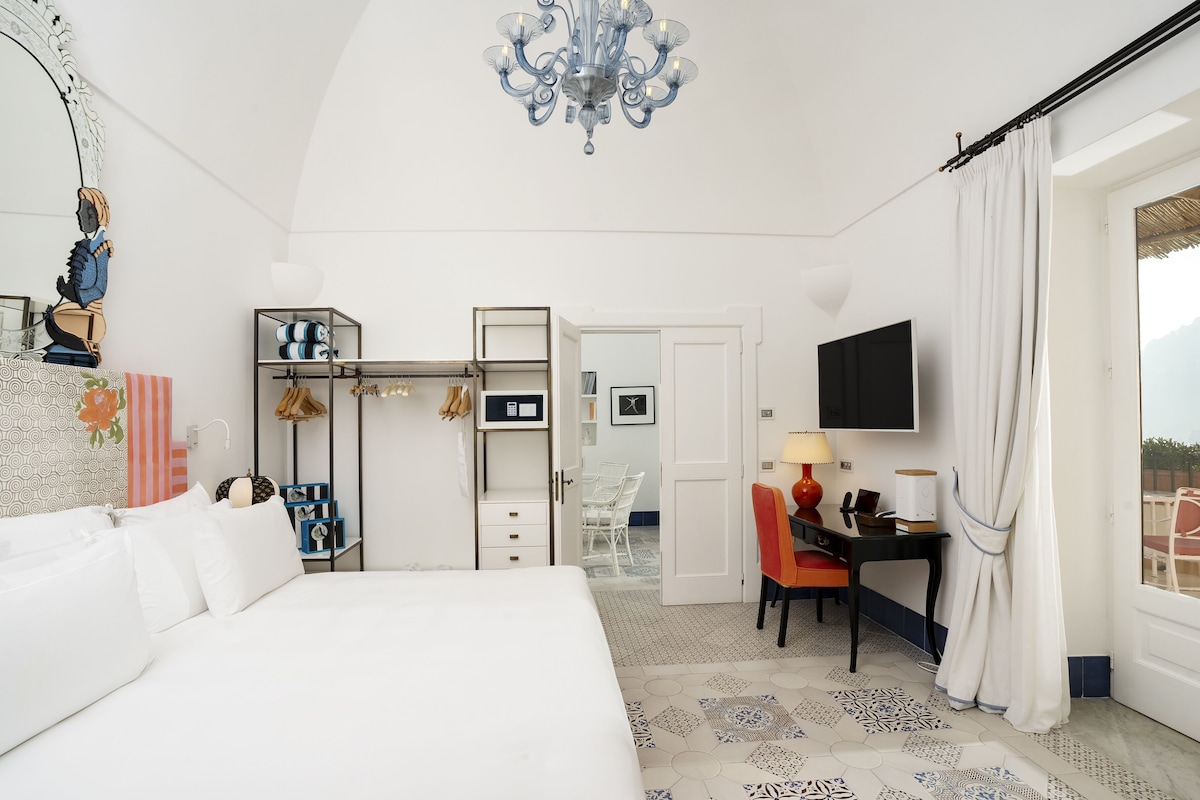 Una habitación de hotel con una cama grande, un escritorio con una silla, un televisor y un armario.