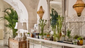Un baño lujoso con decoración ornamental, que incluye un espejo grande, lámparas decorativas y una variedad de plantas.