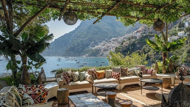 Un área de estar al aire libre con vistas al mar y a las montañas.