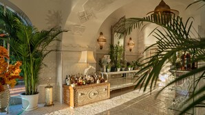 Un lobby lujoso con piso de mármol, una zona de bar decorativa y plantas en macetas.