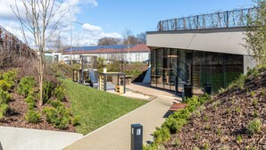 A modern building with large glass windows, a paved pathway, and a landscaped area with shrubs and trees. - Gdańska 21R /5 (Gdansk)