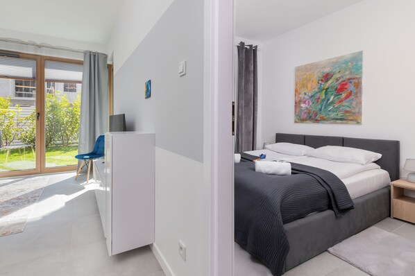 A modern bedroom with a large bed, a desk, and a view of the outdoors. - Gdańska 21R /5 (Gdansk)