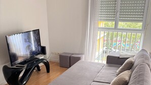 A modern living room with a grey sofa, a flat-screen TV, and a glass coffee table. - Two-room apartment in Chartrons for 4 people (Bordeaux)