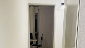 A narrow hallway with wooden flooring leading to a room with a dining table and chairs. - Two-room apartment in Chartrons for 4 people (Bordeaux)