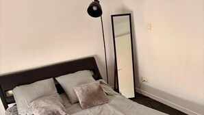 A neatly made bed with a headboard, a bedside lamp, and a mirror on the wall. - Two-room apartment in Chartrons for 4 people (Bordeaux)