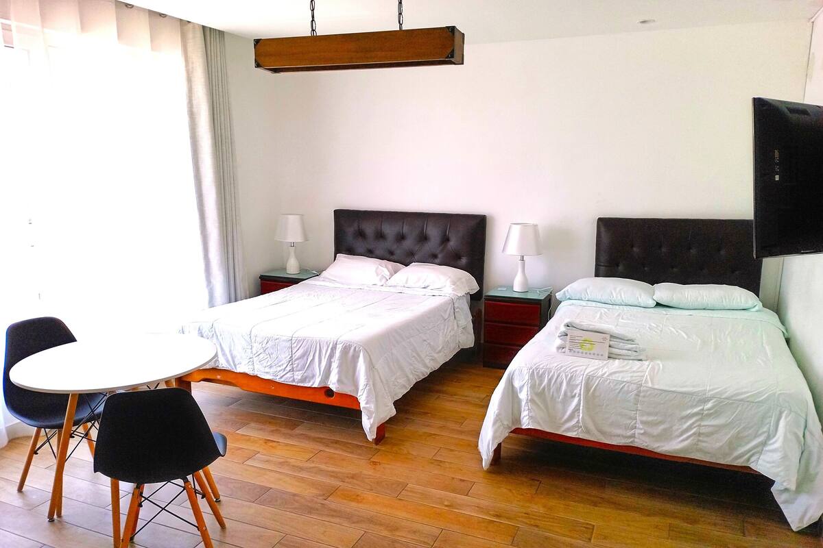 A hotel room with two beds, a dining table, and chairs.