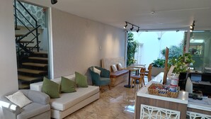 A modern living room with a sofa, chairs, a dining table, and a staircase. - Casablanca (Santiago de Surco)