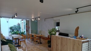 A modern interior with a wooden reception desk, seating area with tables and chairs, and a large window providing natural light. - Casablanca (Santiago de Surco)