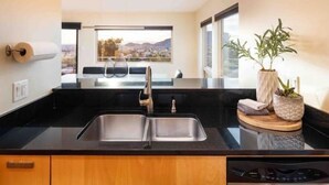 A modern kitchen with a black countertop, stainless steel sink, and wooden cabinets. - “Windmill House” -Mountain/City views, super close to great hiking trails (Phoenix)