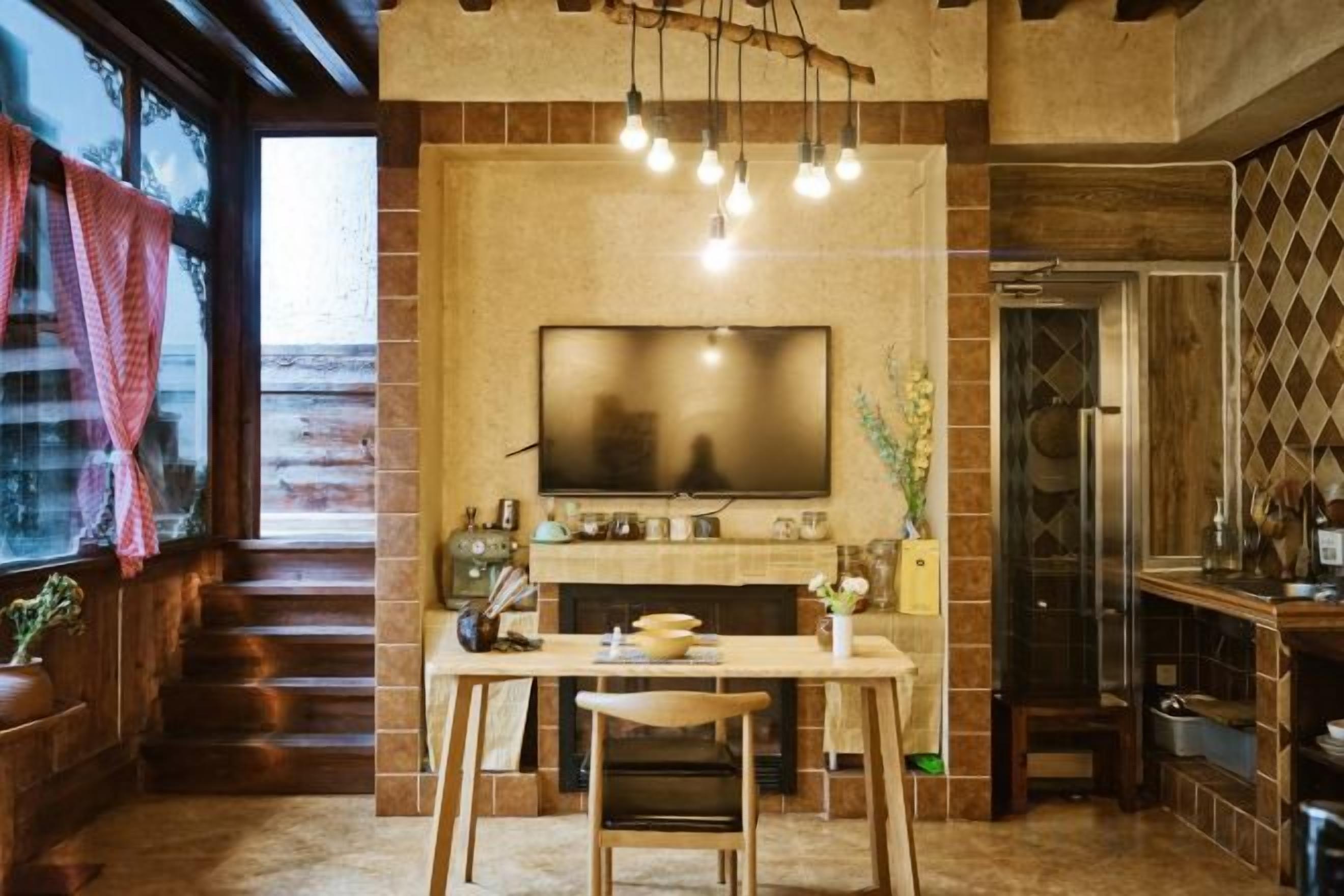 A modern kitchen with a flat-screen TV, wooden dining table, and a staircase leading to an upper level.
