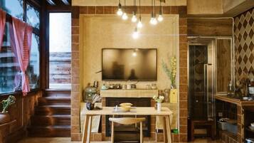 A modern kitchen with a flat-screen TV, wooden dining table, and a staircase leading to an upper level.