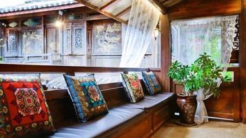 A traditional wooden interior with a bench, patterned cushions, and a potted plant.