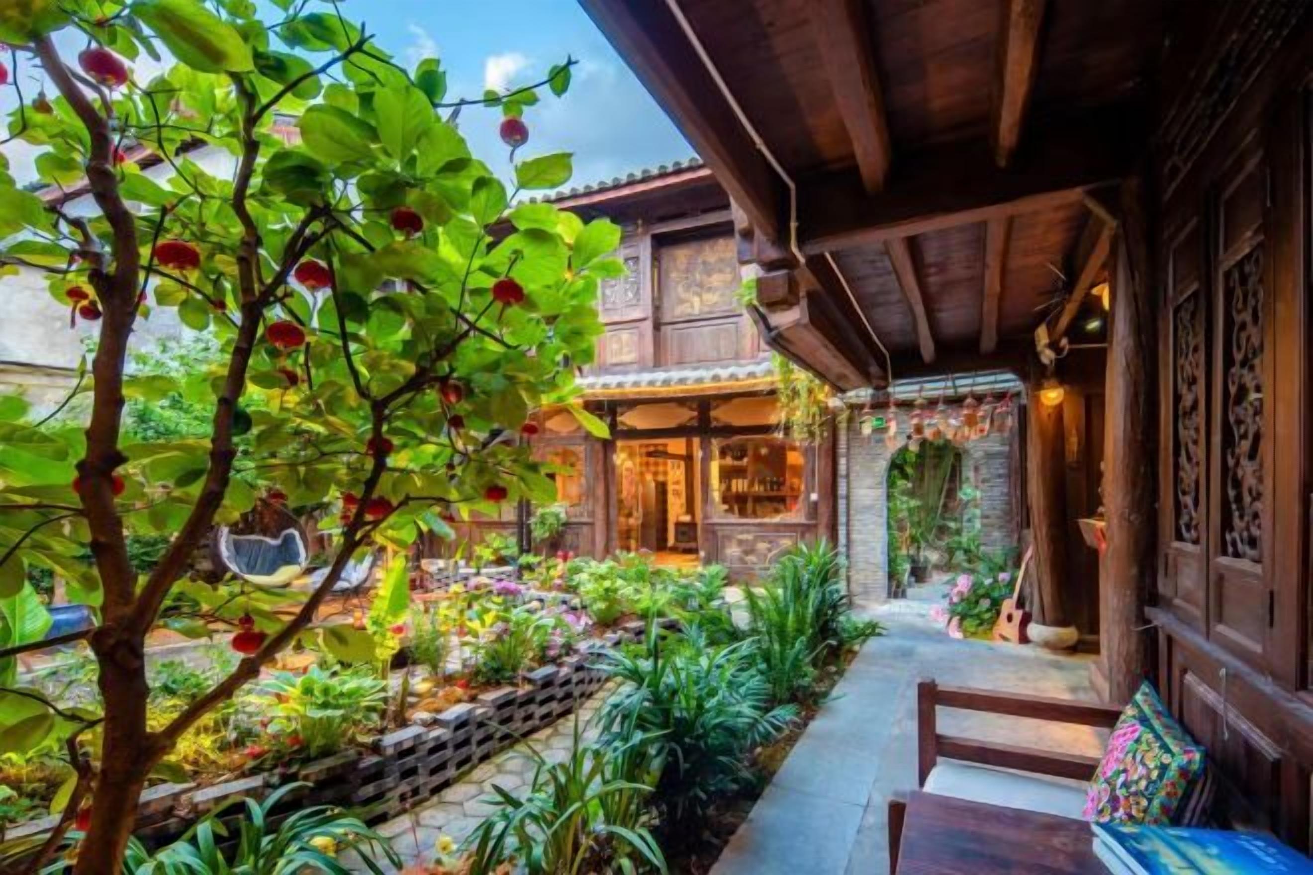 A wooden building with a covered porch, a garden with various plants, and a bench.