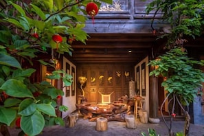 A traditional wooden structure with a central seating area, surrounded by plants and decorative elements. - Lijiang Longfeng Villa (Shuhe Ancient Town Branch) (Lijiang)