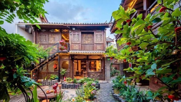 A traditional wooden building with a covered entrance and a small garden area with potted plants and a pathway. - Lijiang Longfeng Villa (Shuhe Ancient Town Branch) (Lijiang)