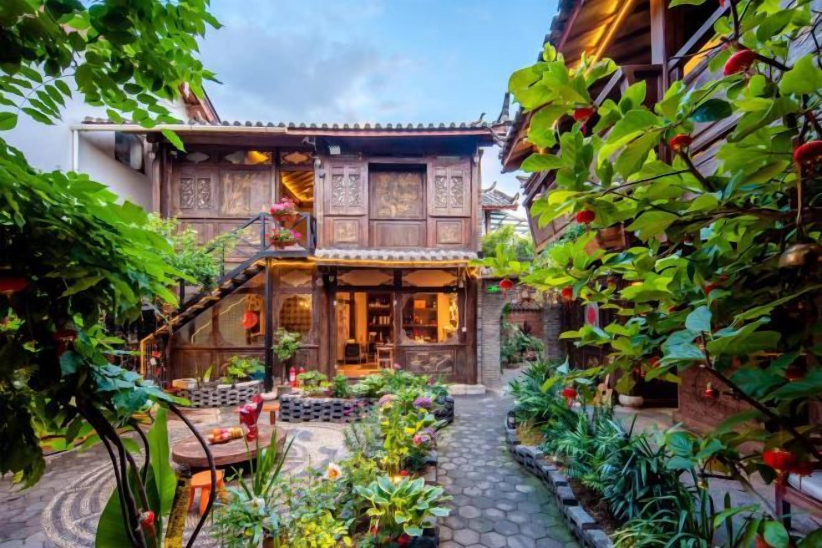 A traditional wooden house with a covered porch, a stone pathway, and lush greenery.
