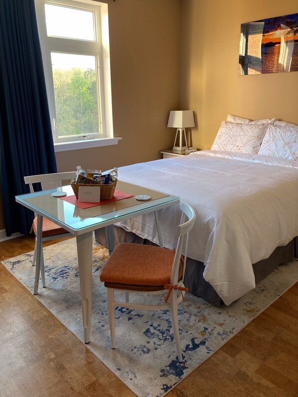 A bedroom with a bed, a bedside table, a chair, a lamp, and a window.