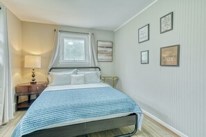 A neatly arranged bedroom with a bed, bedside table, lamp, and wall art.