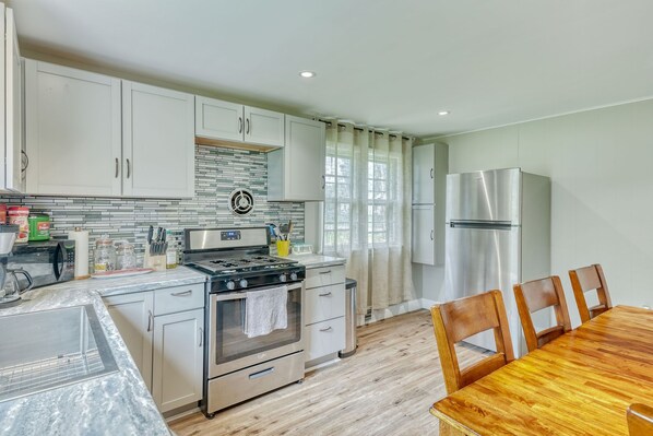 A modern kitchen with white cabinets, a stainless steel stove, and a refrigerator.