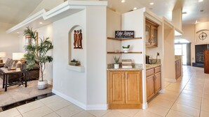 A spacious living area with a large plant, a fireplace, and a kitchen with wooden cabinets. - Lake Havasu City Escape w/ Pool, Patio & Grill! (Lake Havasu City)