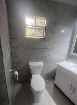 A bathroom with a toilet, a window, and a sink.