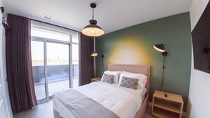 Een moderne hotelkamer met een groot bed, twee nachtkastjes en een uitzicht door een schuifdeur.