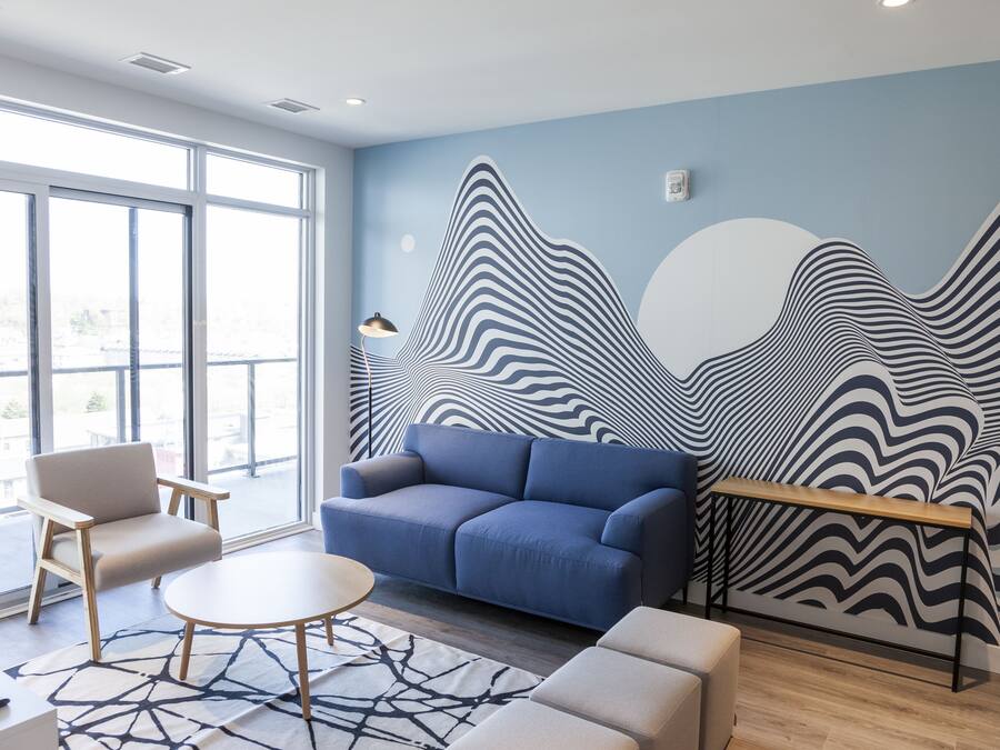 A modern room with a blue sofa, a round table, and a patterned rug.