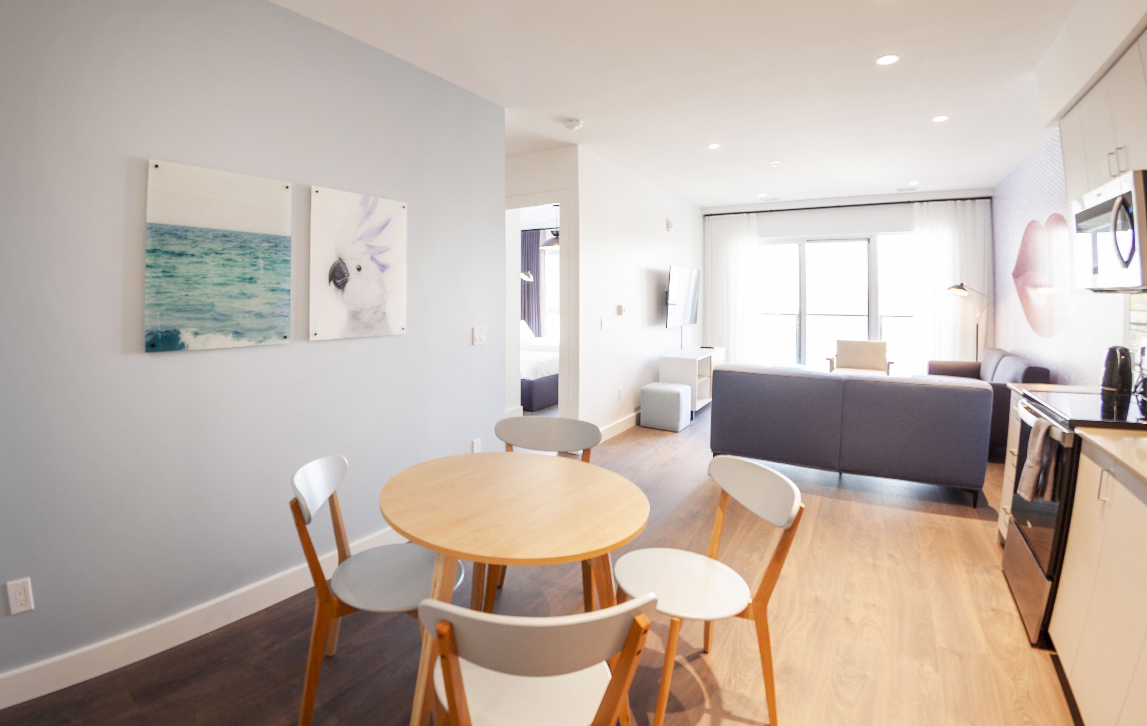 Une chambre d’hôtel moderne dotée d’un coin repas, d’un canapé, d’une cuisine et d’œuvres d’art accrochées aux murs.