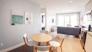 Une chambre d’hôtel moderne dotée d’un coin repas, d’un canapé, d’une cuisine et d’œuvres d’art accrochées aux murs.
