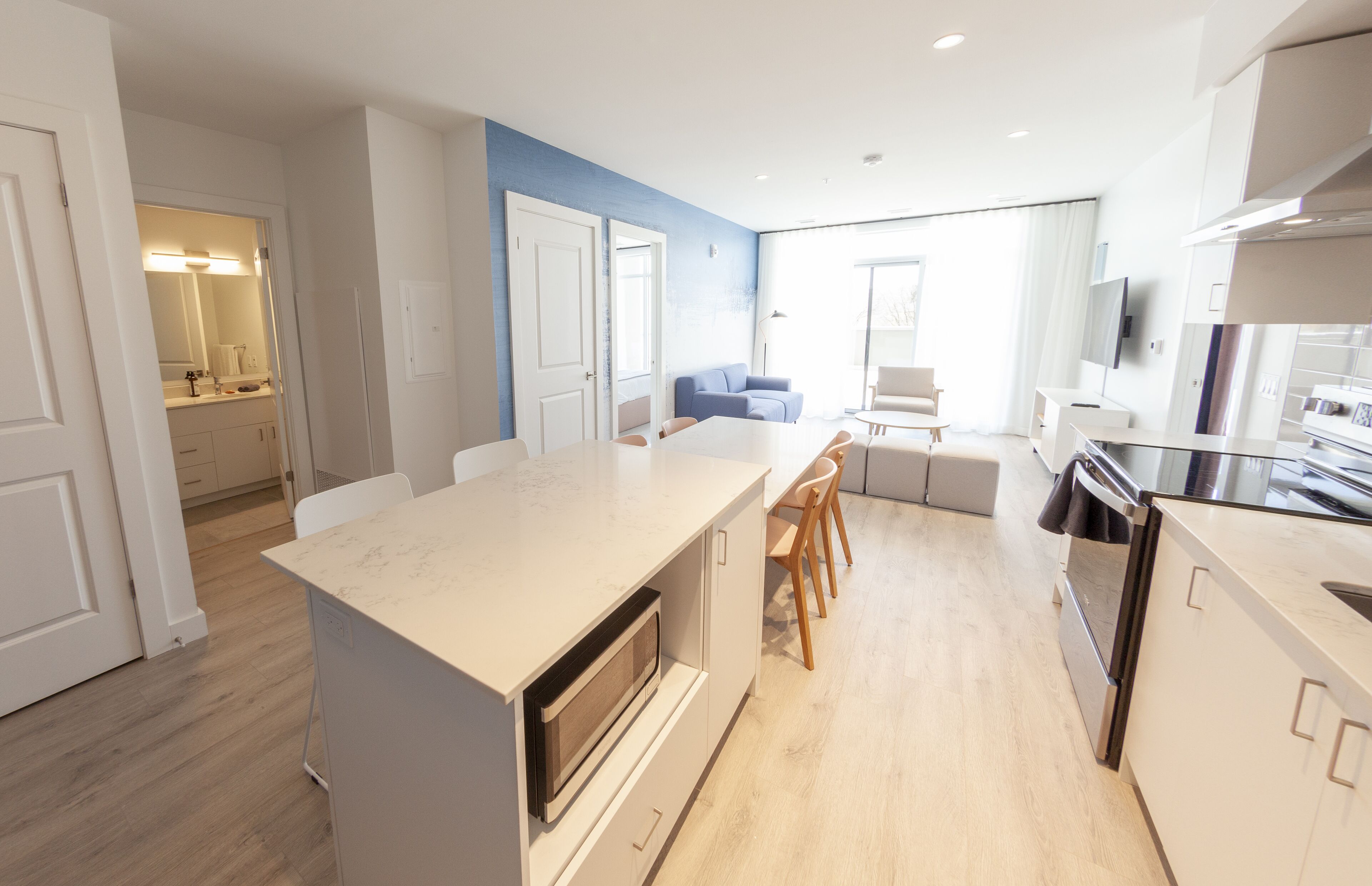 Una cocina moderna con una isla central, sillas de madera y un comedor con sofá.