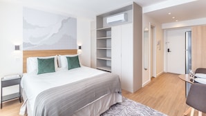 Una habitación de hotel moderna con cama, armario, escritorio y zona de comedor.