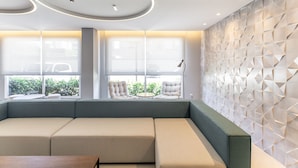 Un interior moderno con sofá modular, mesa redonda y diseño geométrico en la pared.