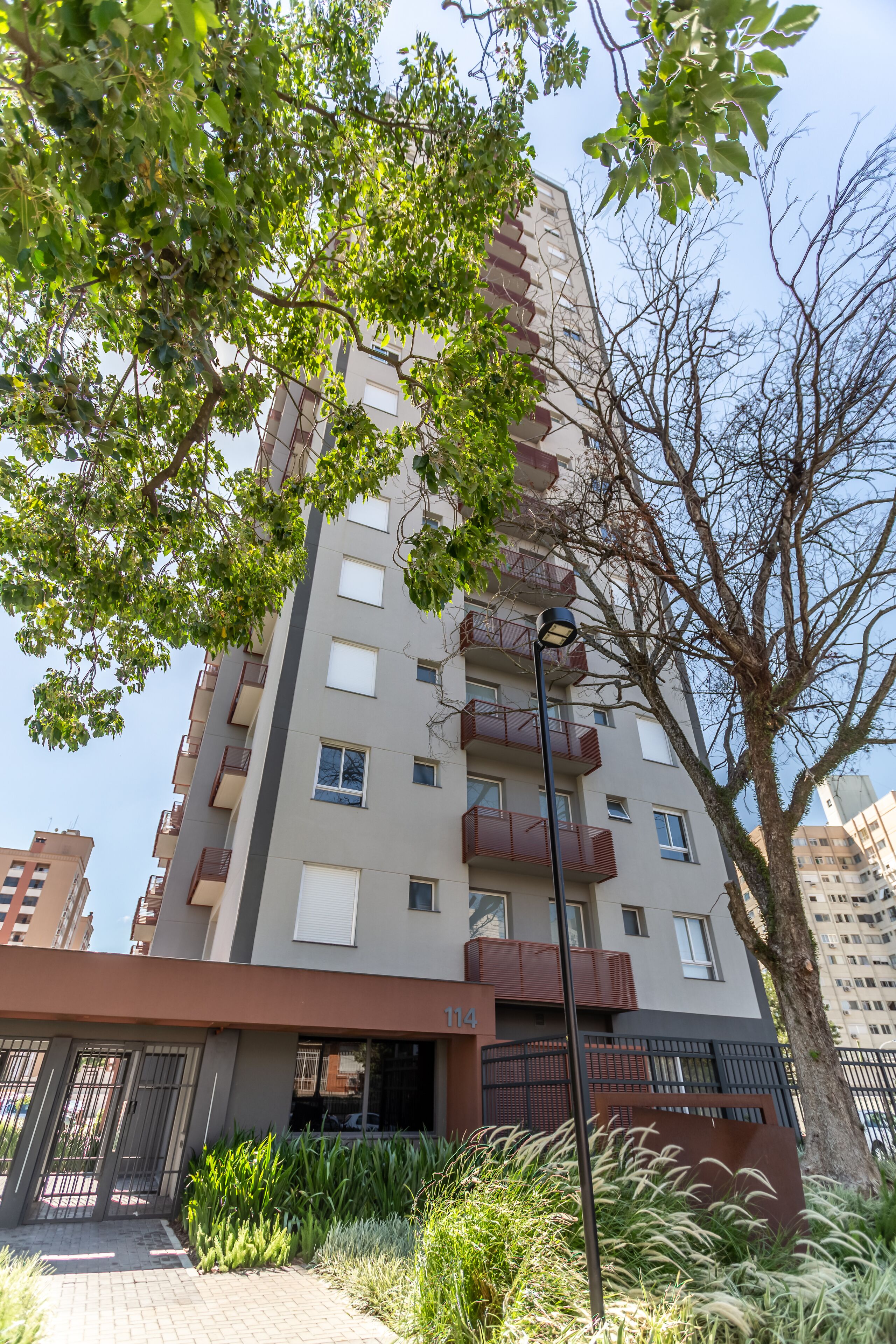 A multi-story residential building with balconies, a gated entrance, and a well-maintained garden area.