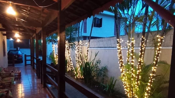 A covered outdoor area with a tiled floor, wooden benches, and string lights. - Haja Luz Pousada em Itaquaquecetuba (Itaquaquecetuba)