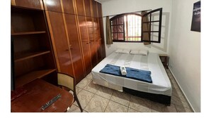 A bedroom with a bed, a wardrobe, a window, and a table. - Haja Luz Pousada em Itaquaquecetuba (Itaquaquecetuba)