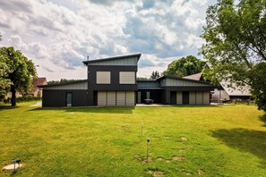 Ein modernes, zweistöckiges Haus mit großem Vorgarten, Garagen und einem Weg zum Eingang.