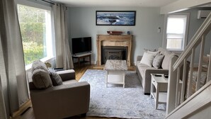 Una sala de estar con chimenea, un sofá, un televisor y una escalera.