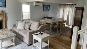 Una sala de estar con sofá, mesa de centro y comedor con mesa y sillas.