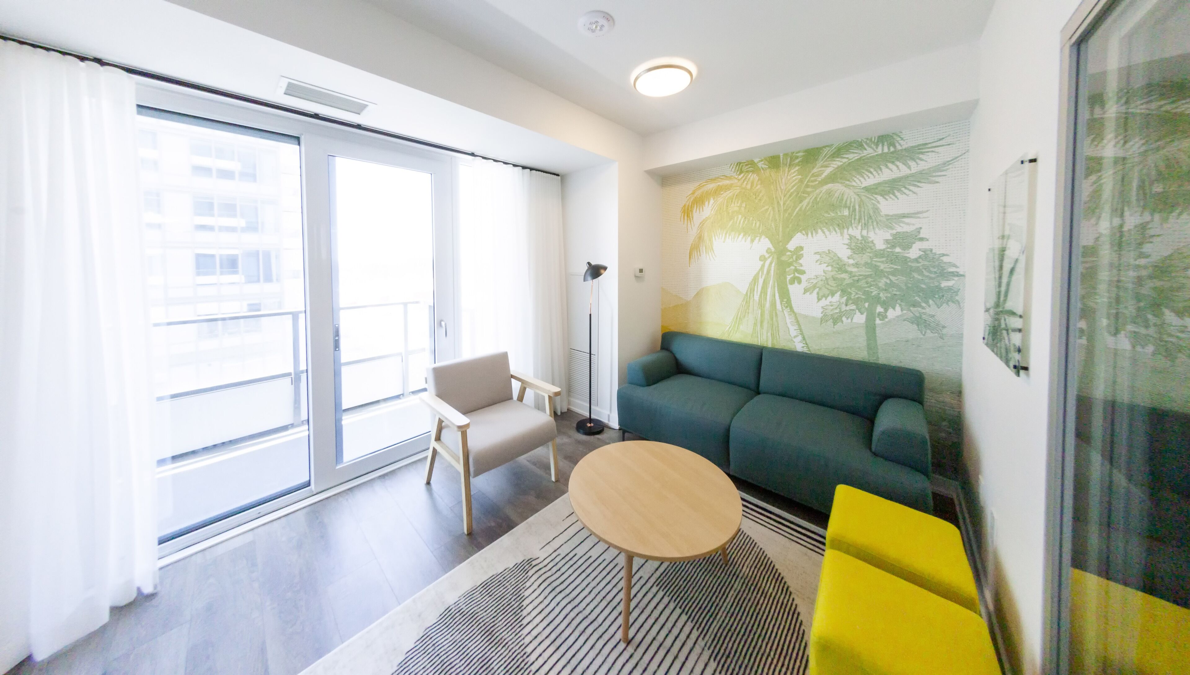 Een moderne woonkamer met een bank, een klein rond tafeltje, een stoel en een groot raam.