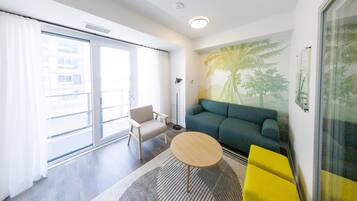 Een moderne woonkamer met een bank, een klein rond tafeltje, een stoel en een groot raam.